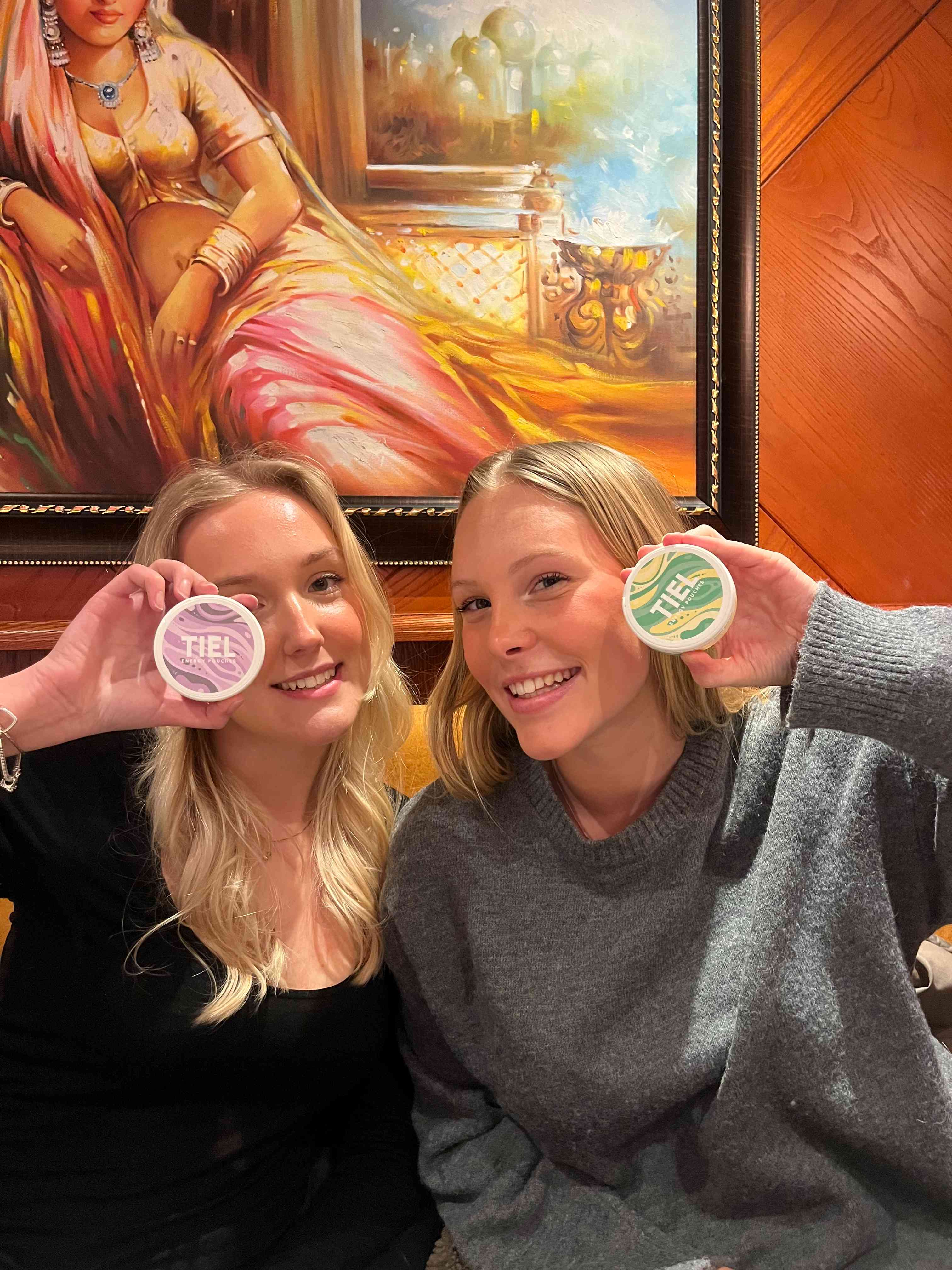 UGC-bild med två vänner som håller varsin TIEL energy pouches dosa – nikotinfritt snus med koffein i smakerna sweet elderflower och viol & lakrits